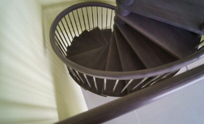 Drewniane schody kręte z metalowymi balustradami