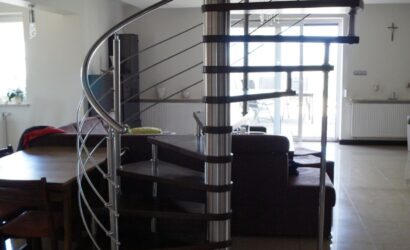 Drewniane schody kręte z metalowymi balustradami