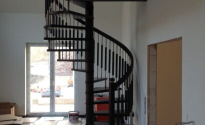 Drewniane schody kręte z metalowymi balustradami