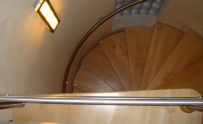Drewniane schody kręte z metalowymi balustradami
