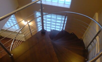 Drewniane schody kręte z metalowymi balustradami