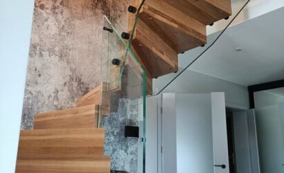 Drewniane schody wewnętrzne ze szklanymi balustradami