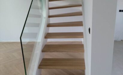 Drewniane schody wewnętrzne ze szklanymi balustradami